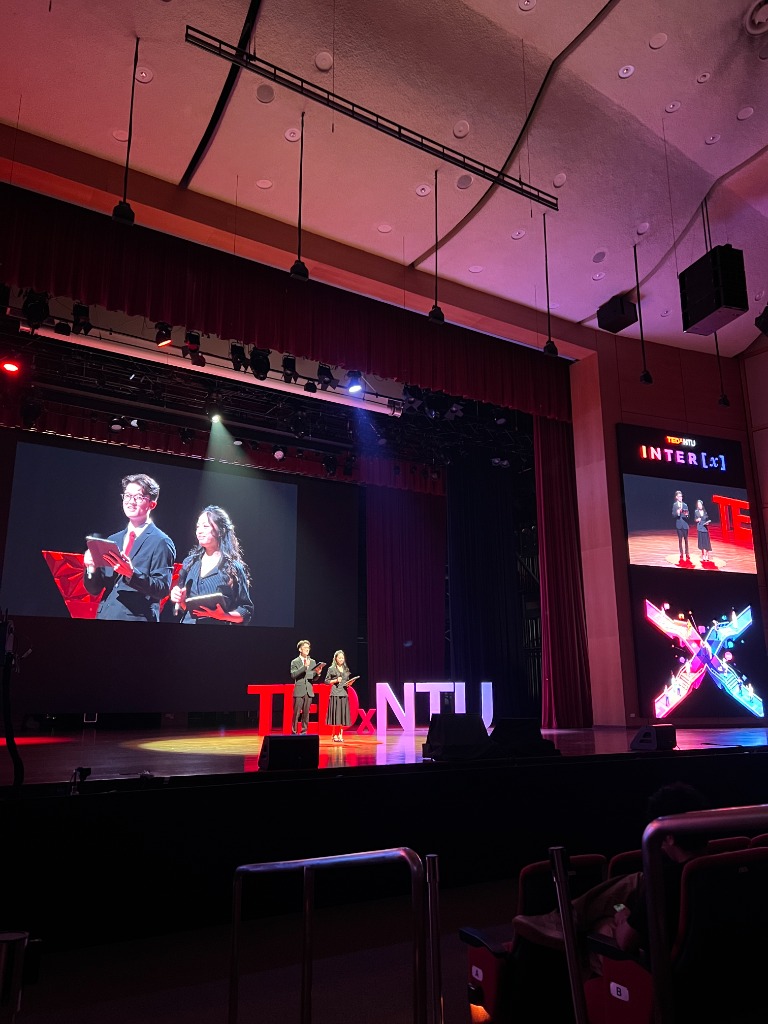 Hosts and speakers on stage introducing TEDxNTU Inter[X] at Nanyang Auditorium.