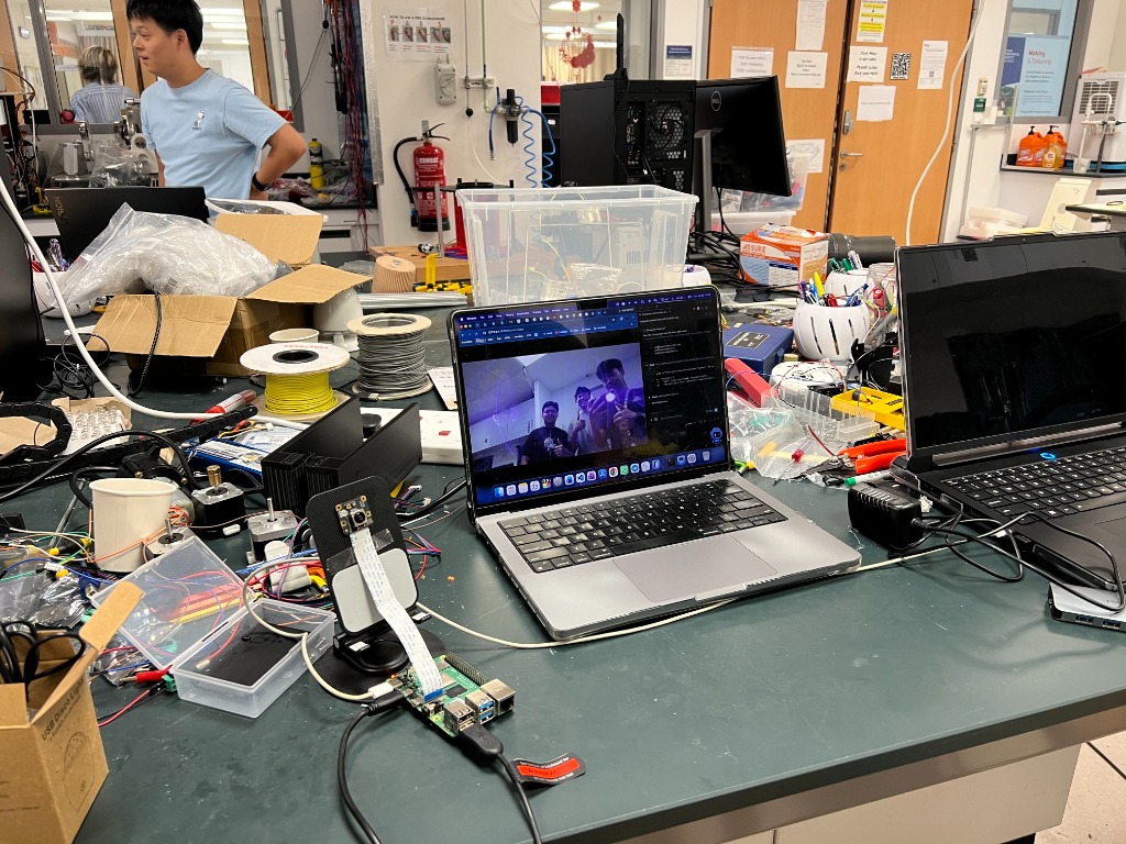 Raspberry Pi camera test rig, breadboards, 3D printing filaments, and laptop streaming video in the NTU lab.