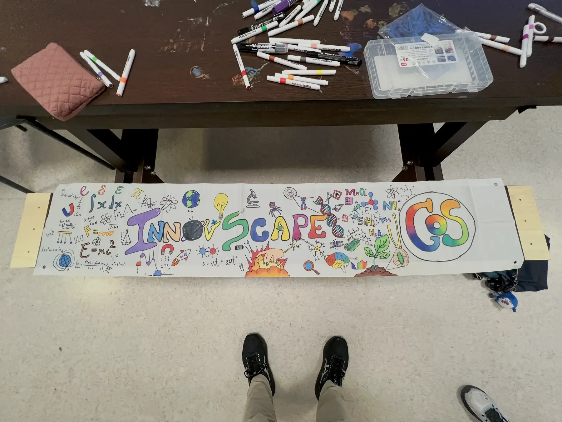 Hand-drawn InnovScape banner with colourful science illustrations and markers on the table above it.